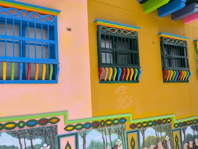 Fachada amarilla con zócalos y balcones de colores en Guatapé
