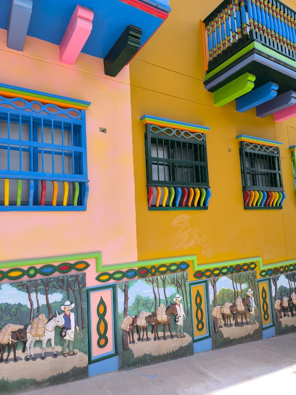 Fachada amarilla con zócalos y balcones de colores en Guatapé