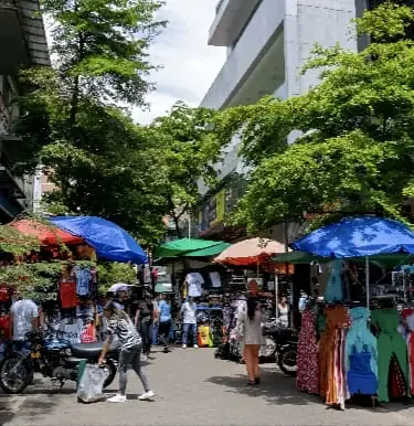 Calle comercial con toldos y vendedores en el centro de Medellín, El Hueco
